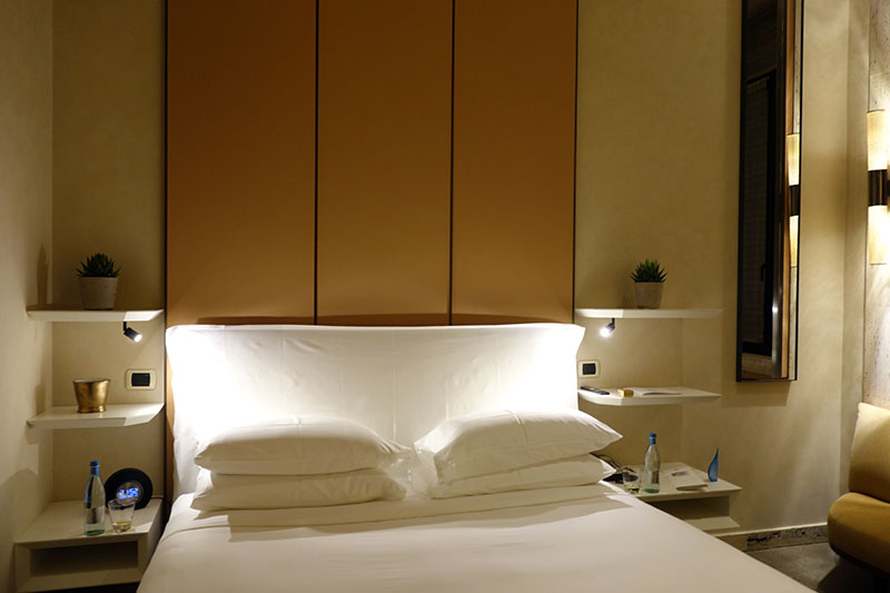 a bed with white pillows and a shelf with a plant on it