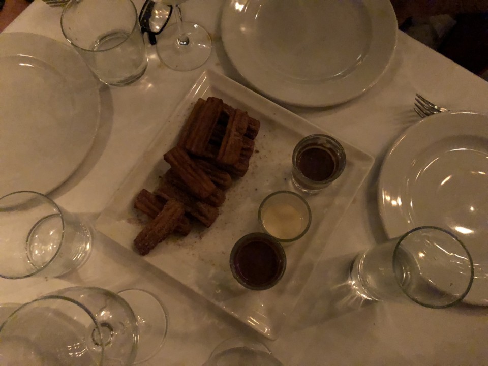 a plate of churros and glasses on a table