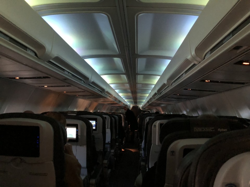 inside an airplane with seats and a person standing in the back