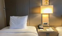a bed with a lamp and a telephone