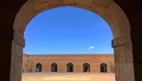 a stone archway with people walking in the background