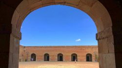a stone archway with people walking in the background