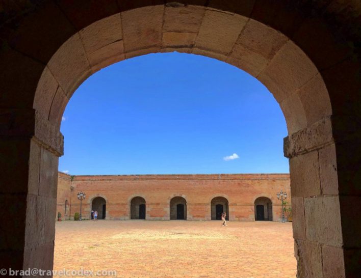 a stone archway with people walking in the background