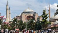 a group of people walking in a park with a large building with Hagia Sophia in the background
