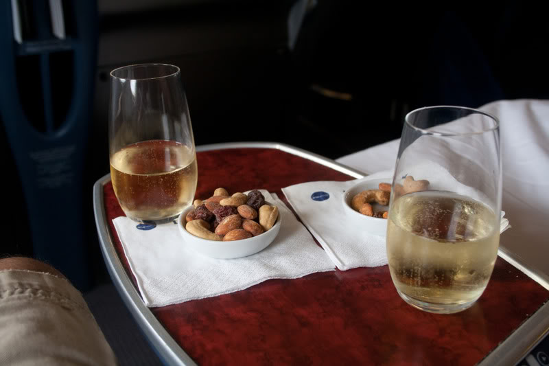 a bowl of nuts and a glass of wine on a tray