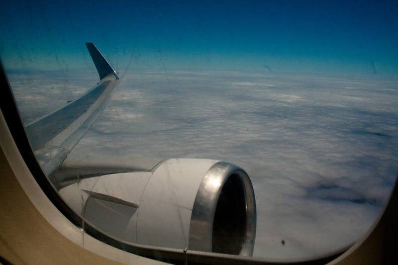 an airplane wing with a blue sky and clouds