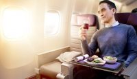 a man sitting in an airplane with a glass of wine