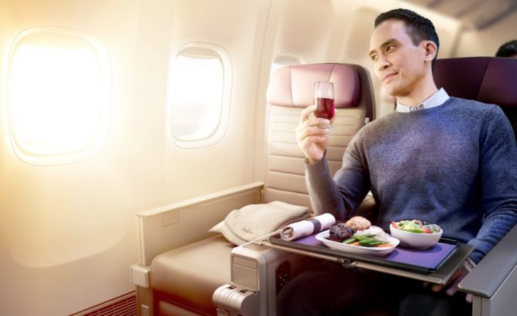 a man sitting in an airplane with a glass of wine