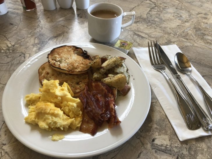 a plate of breakfast with eggs bacon and coffee