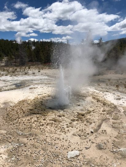 a geyser erupting in a dirt field