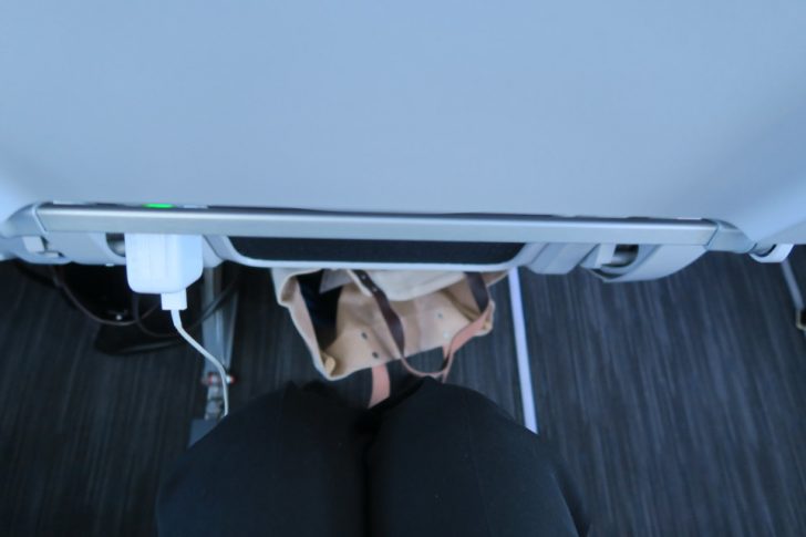 a person's legs and a bag under a seat