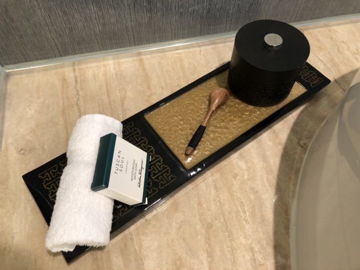 a black and gold tray with a brush and a white towel on a marble surface