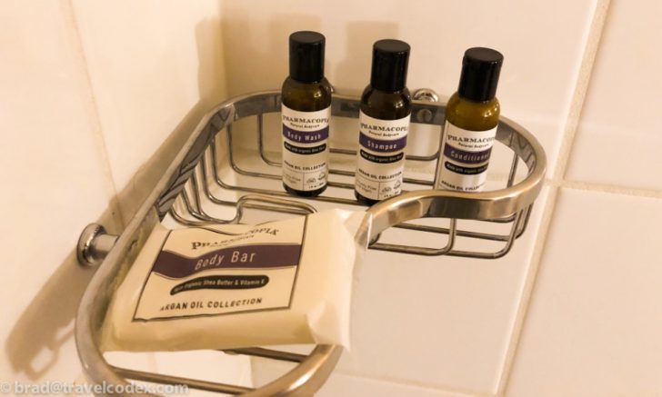 a shower caddy with small bottles of shampoo and a bag of body bar