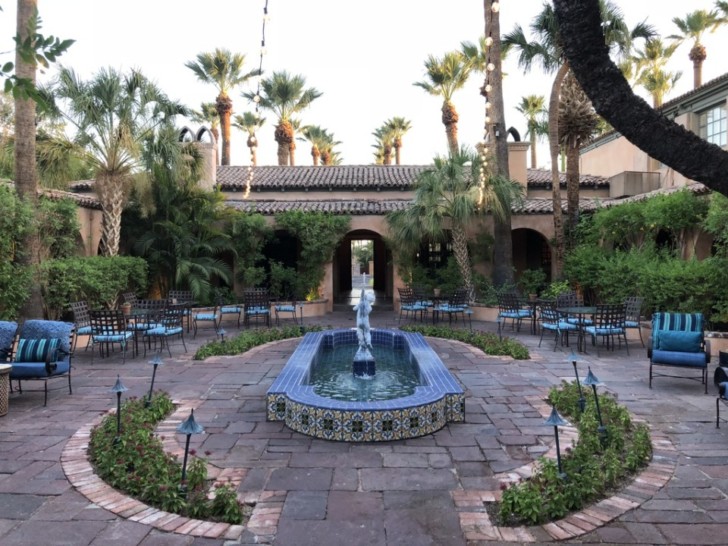 a courtyard with a fountain and chairs