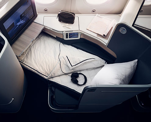 a bed with headphones and a monitor on the side of the seat