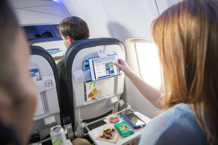 a woman pointing at a tablet on a plane