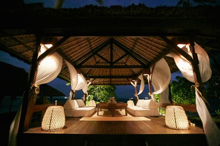 a gazebo with white furniture and lights