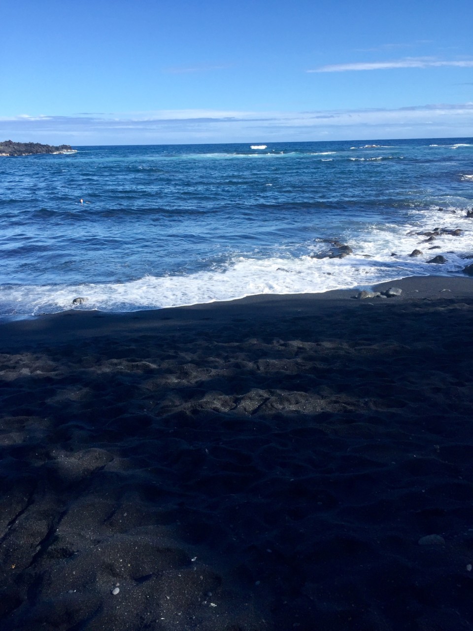 a black sand beach with waves crashing on the shore