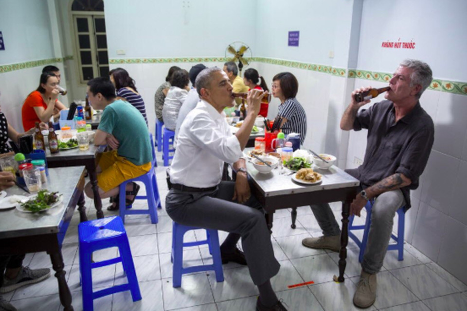 a group of people sitting at a table eating food and drinking