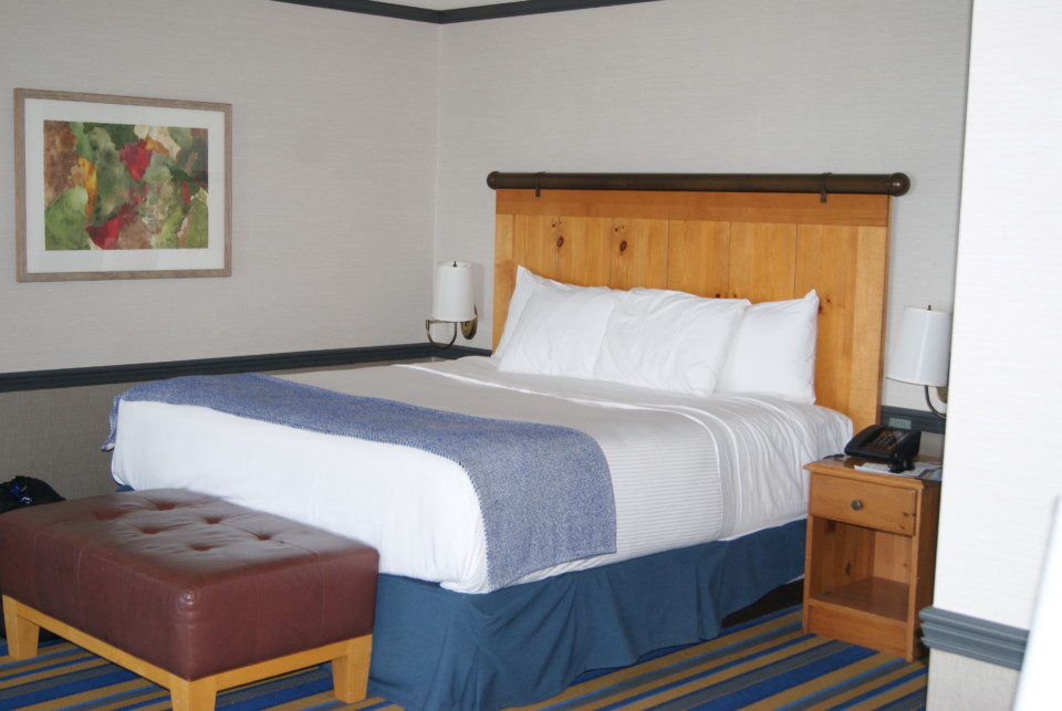 a bed with a wood headboard and a lamp
