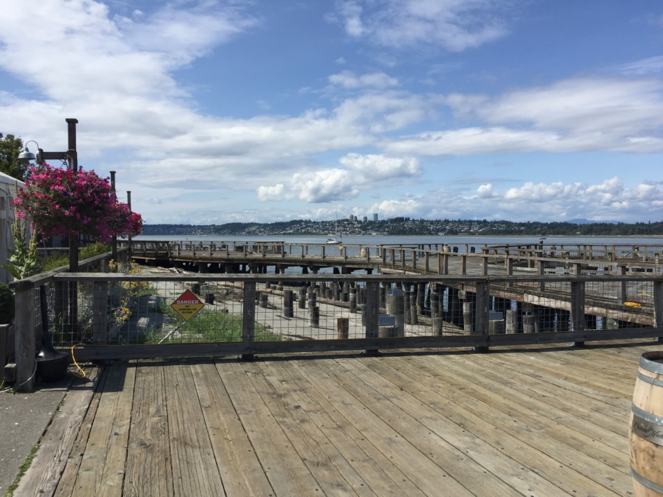 a wooden deck with a fence and a dock with water in the background