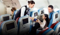 a woman giving a teddy bear to a child on an airplane