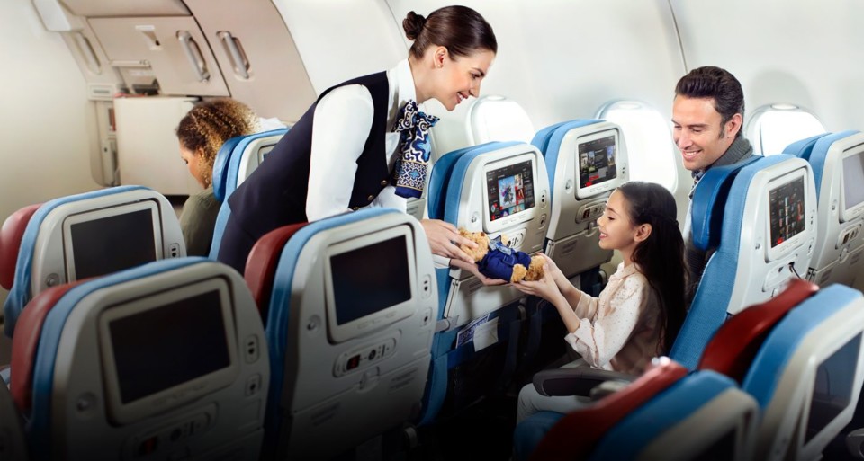 a woman giving a teddy bear to a child on an airplane