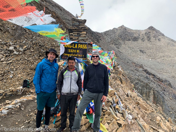 a group of men standing in front of a sign on a mountain