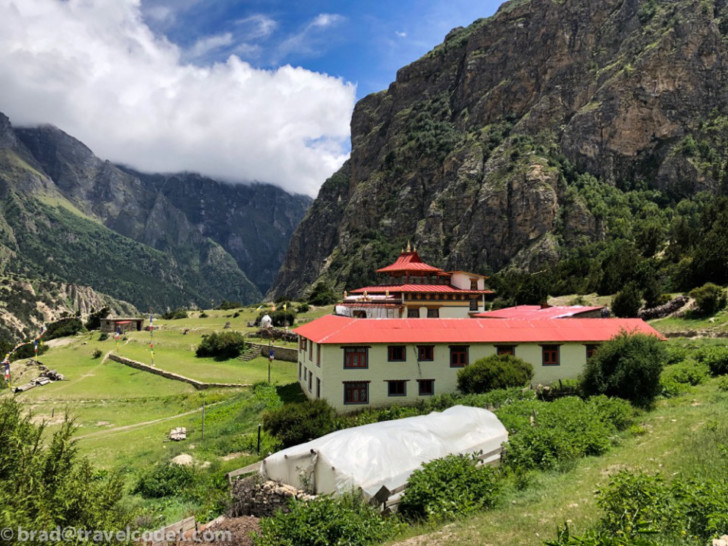 a building with a red roof in a valley with mountains