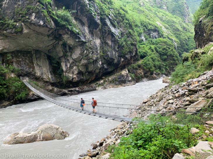 people walking on a suspension bridge over a river