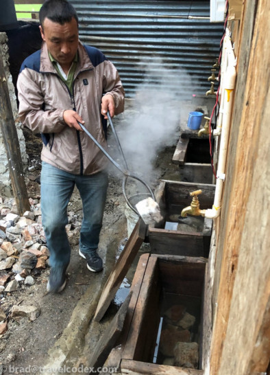 a man holding a metal tongs over a water fountain