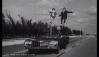 a man and woman jumping off a pole in the middle of a road