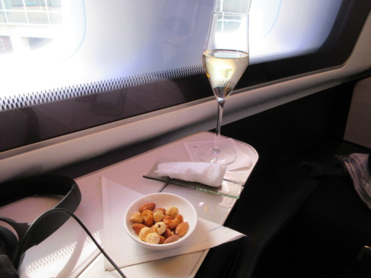 a glass of wine next to a bowl of nuts