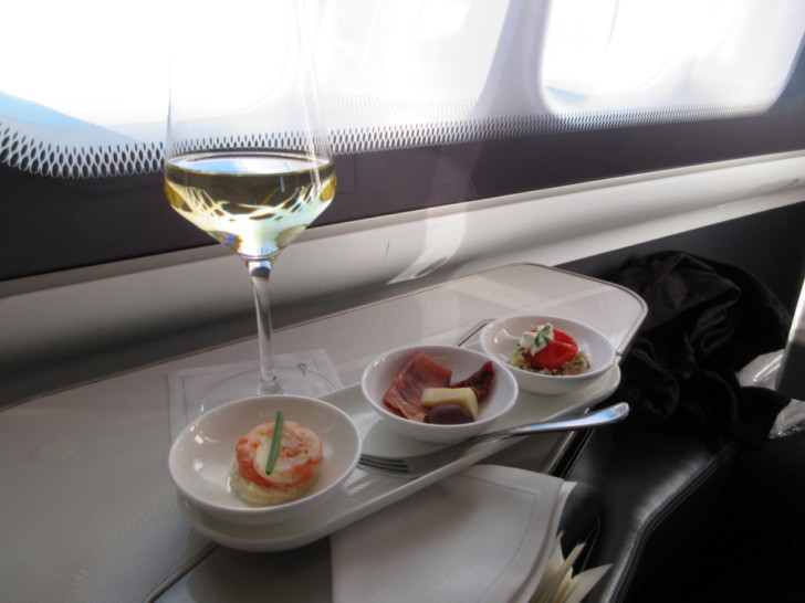 a glass of wine next to a tray of food