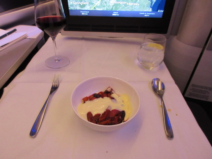 a bowl of food on a table with a glass of wine and a computer