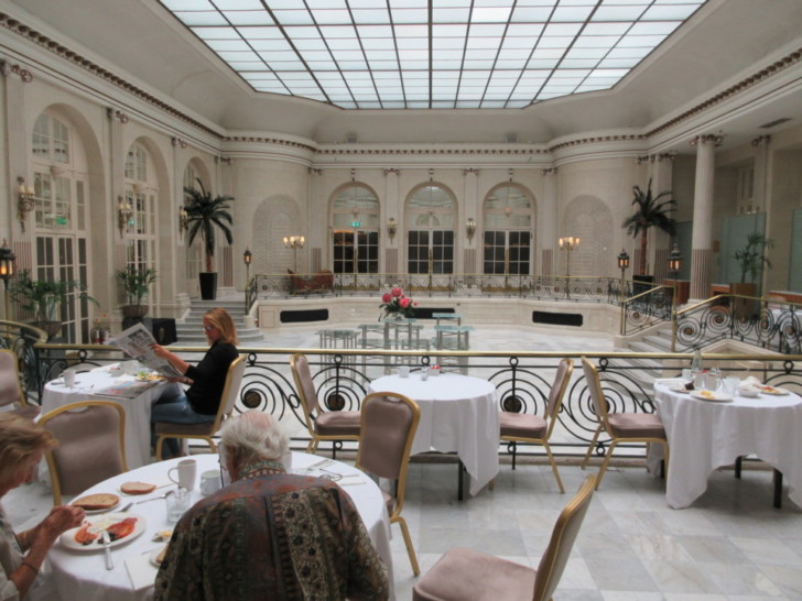a group of people sitting at tables in a room with a glass ceiling