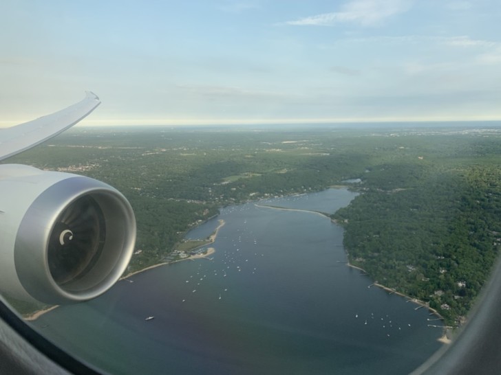 an airplane wing with a body of water and land below