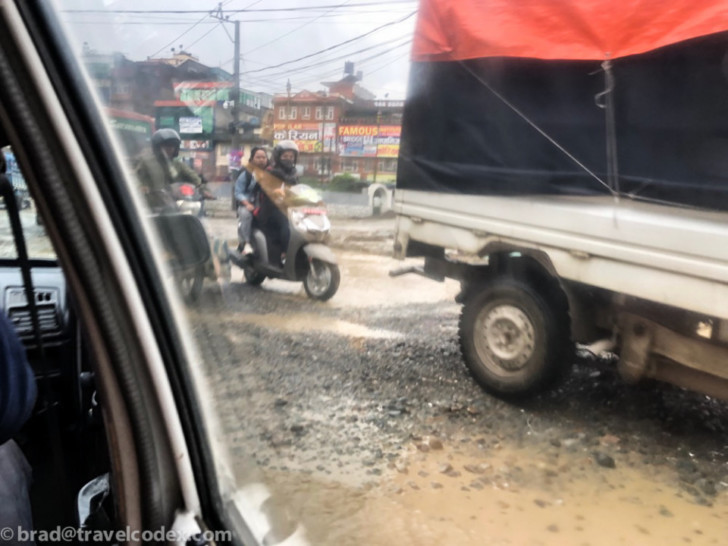 a group of people riding a motorcycle on a wet road