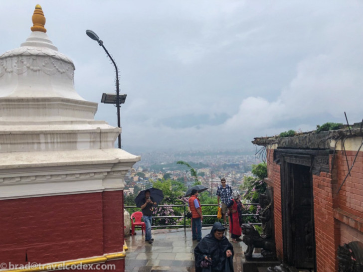 a group of people standing on a ledge with umbrellas