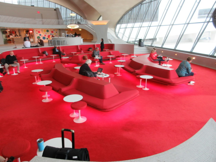 people sitting in a red area with tables and chairs