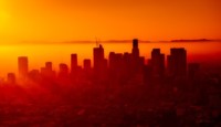 a city skyline with the sun shining through
