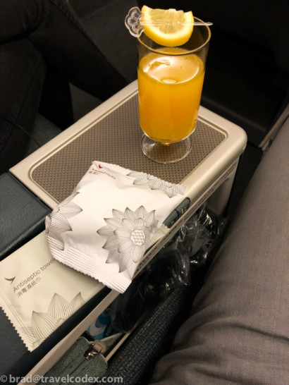 a glass of orange juice and a packet of sugar on a table
