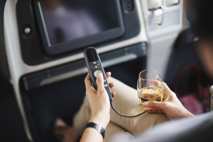 a person holding a remote control while sitting on an airplane