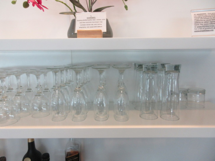 a shelf with wine glasses and a sign