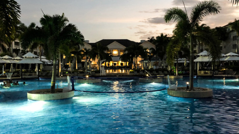 a pool with palm trees and buildings in the background