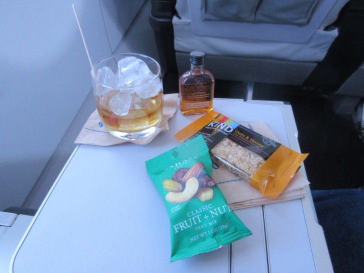 a glass of alcohol and snacks on a table