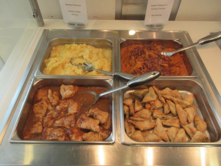 a tray of food with a few silver tongs