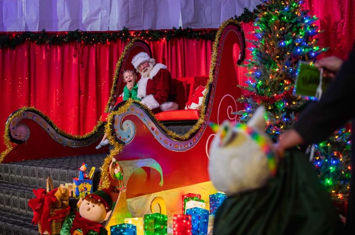 a group of kids in a sleigh with a christmas tree and lights