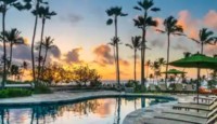 a pool with palm trees and a sunset