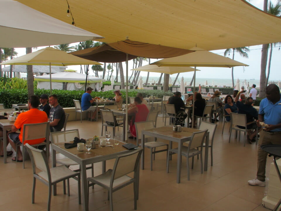a group of people sitting at tables and chairs under a canopy